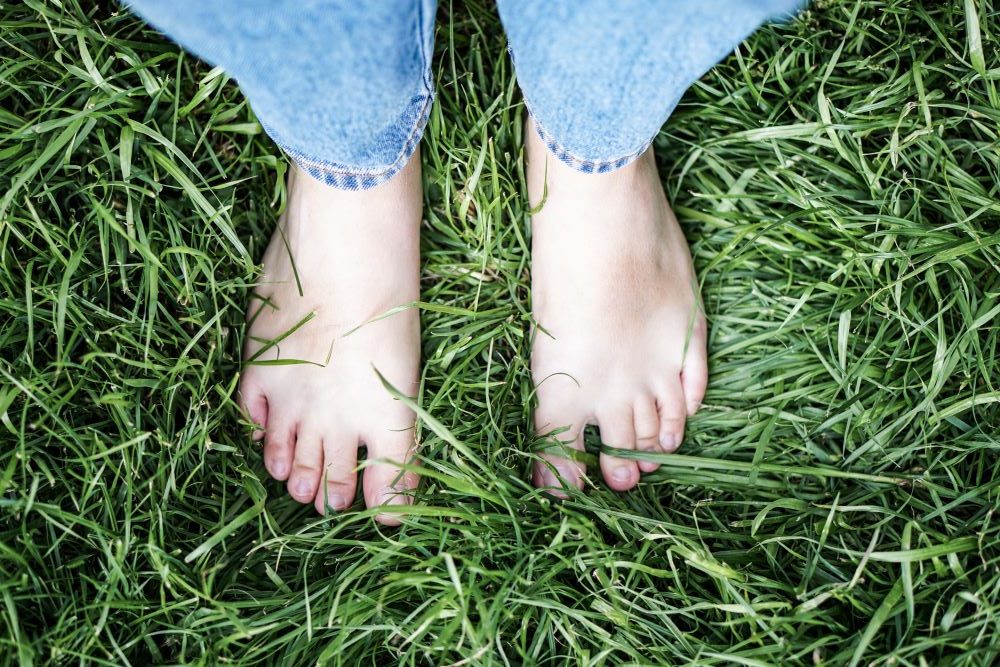 Nackte Füße auf grünem Gras als Aufmacherbild für das Kontaktformular des Magazins Podologie