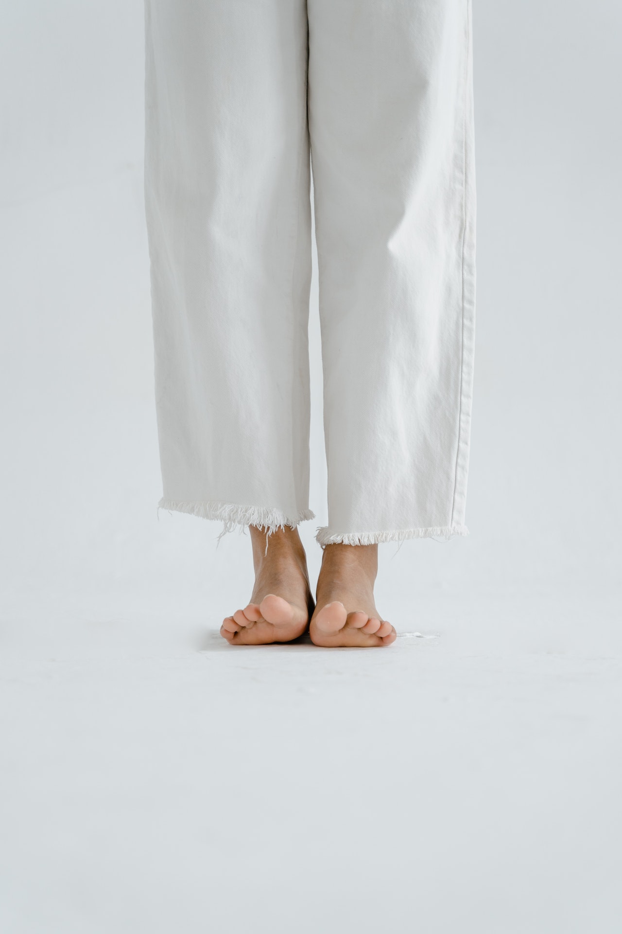 Blick auf eine weiße Jeans uns nackten Füße zur Illustration der Abonnement-Möglichkeiten des Magazins Podologie
